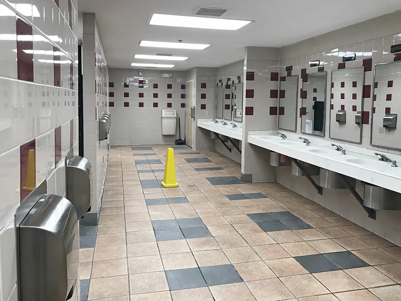 A long hallway with lots of sinks and mirrors in a public restroom.