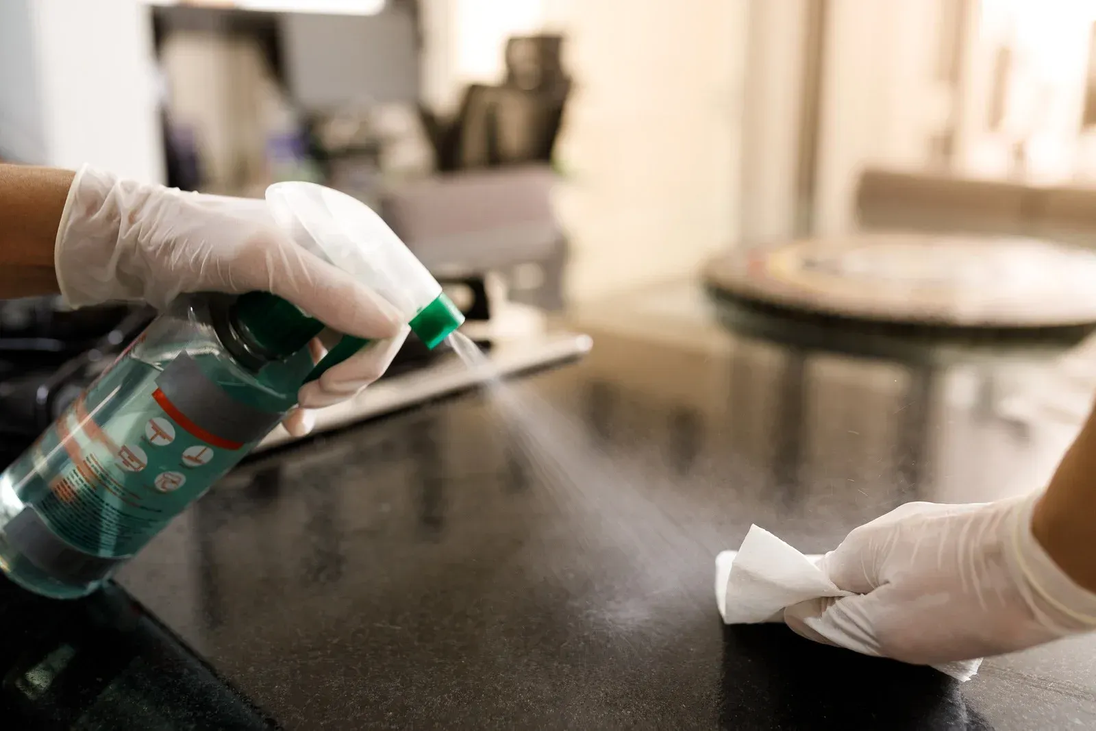 A person is cleaning a counter with a spray bottle and a cloth.