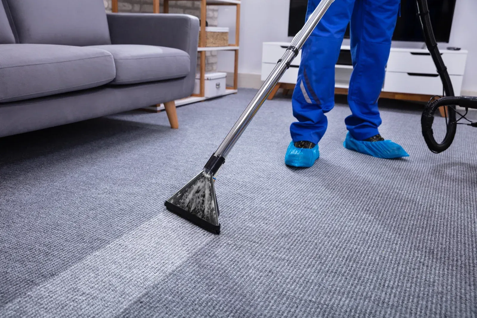 A person is cleaning a carpet with a vacuum cleaner in a living room.