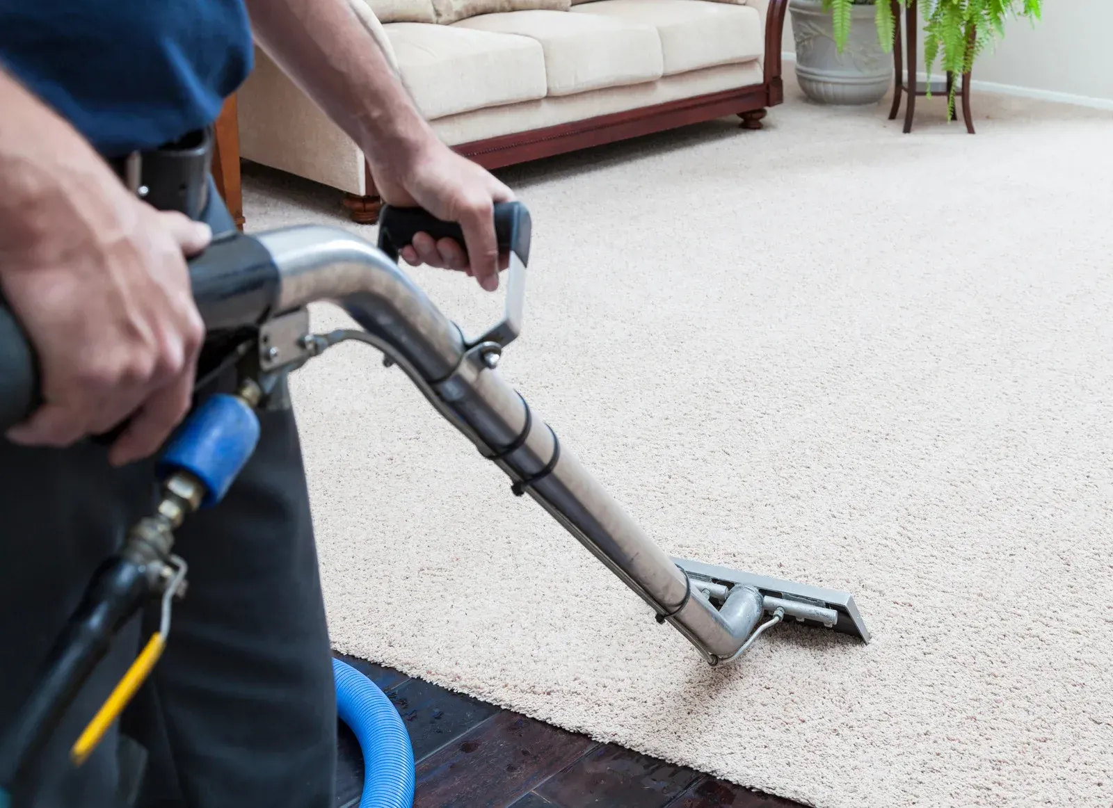 A man is using a vacuum cleaner to clean a carpet in a living room.