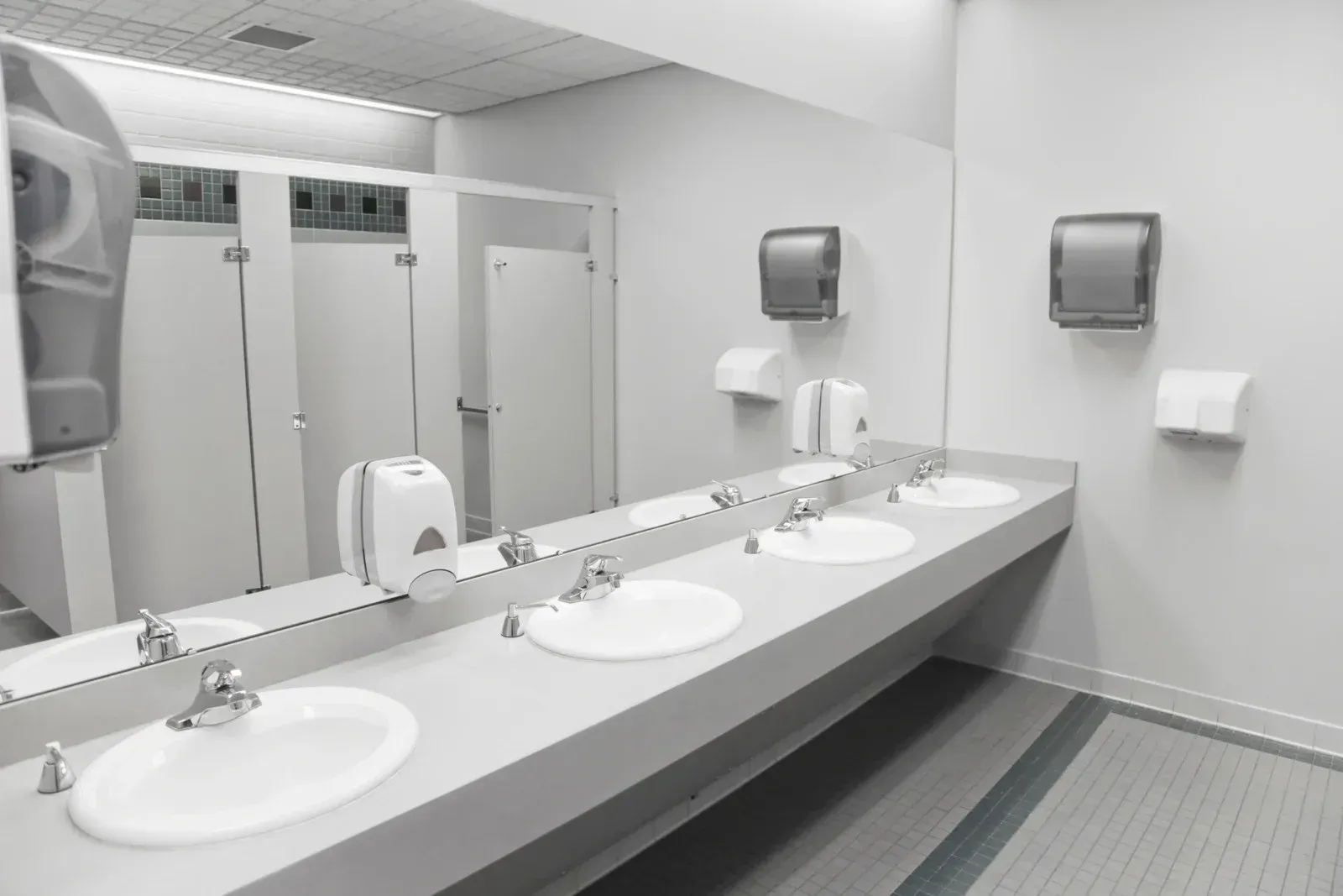A public restroom with a row of sinks and mirrors.