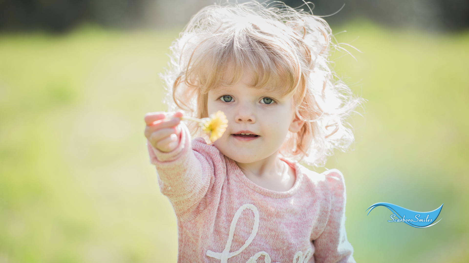 A little girl is holding a flower in her hand.