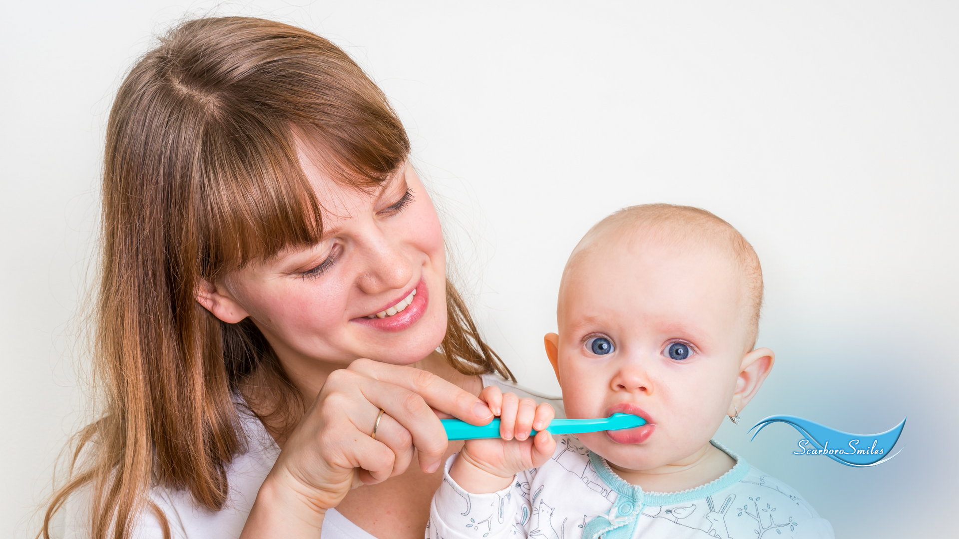 A woman is brushing a baby 's teeth with a blue toothbrush.