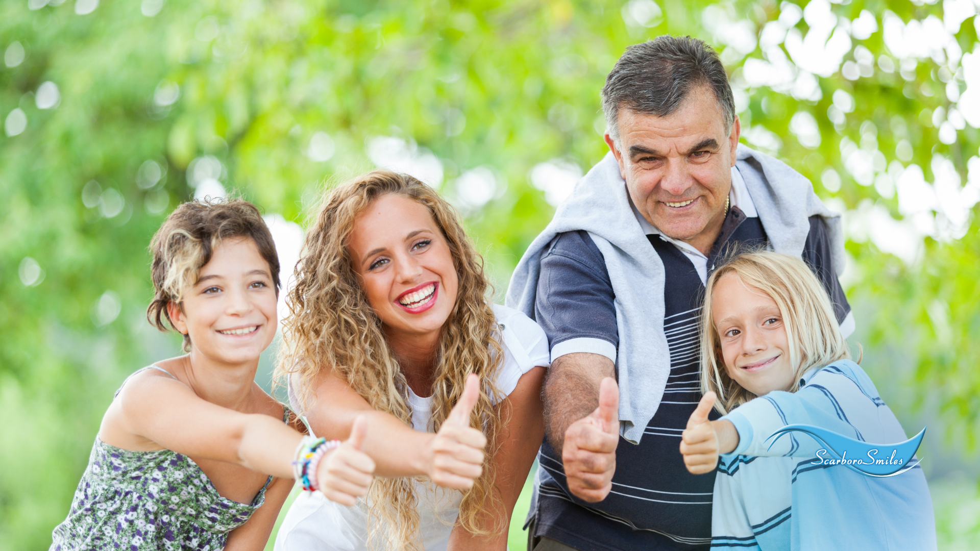 A family is giving a thumbs up in a park.