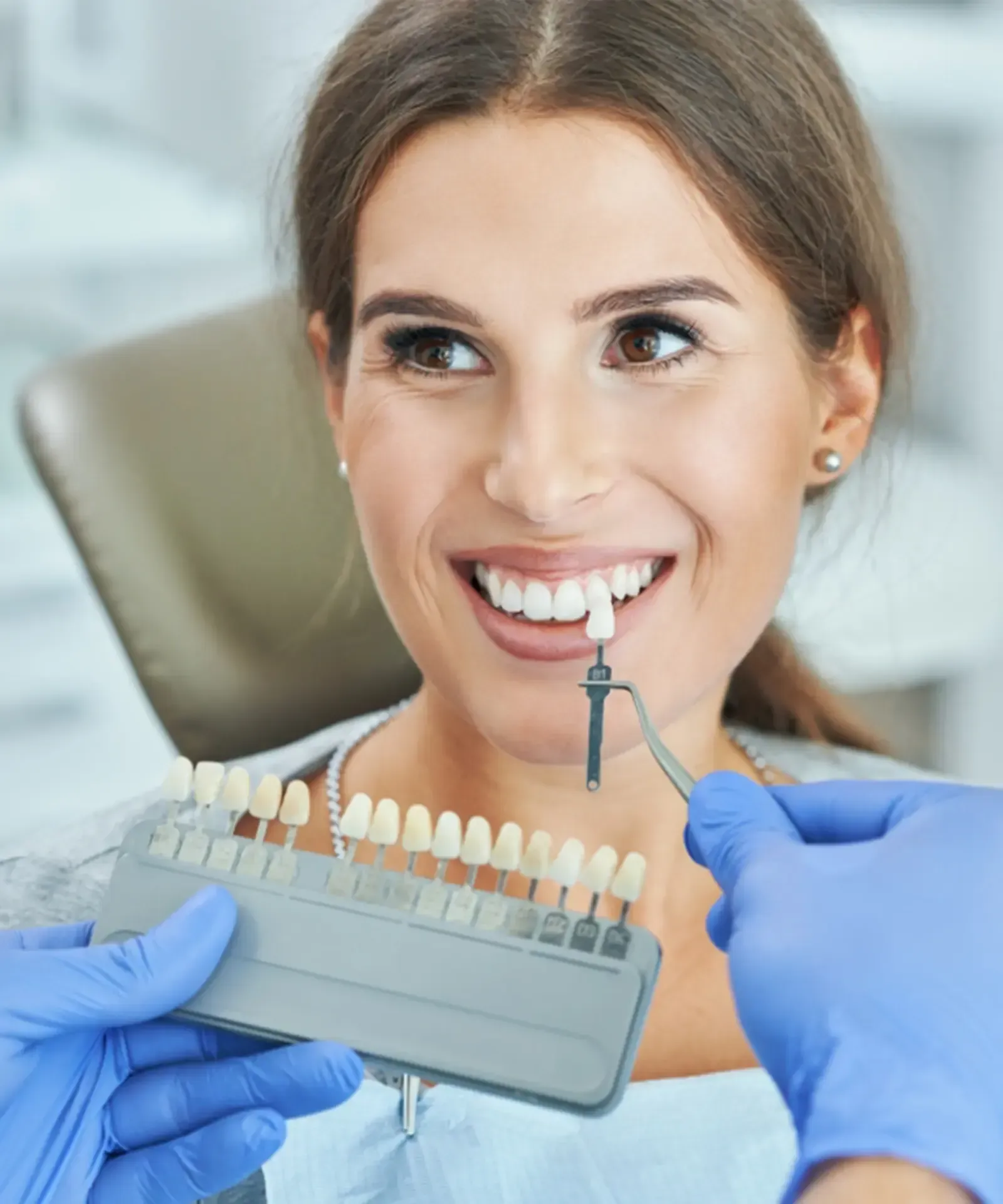 Woman with dark hair smiling, wearing teal scrubs, set against a wood-paneled wall.