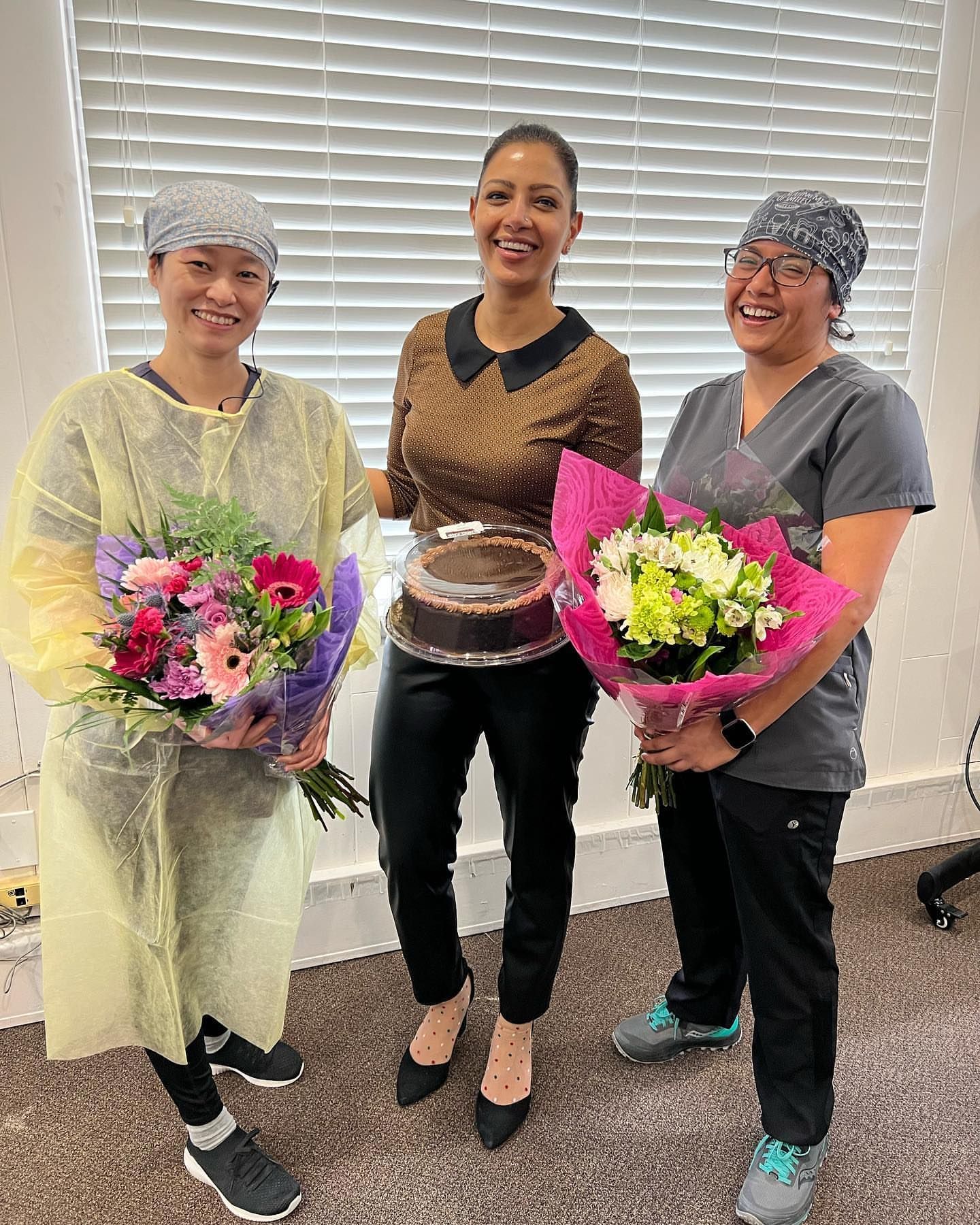 Dr. Amita Bajwa and other 2 two people holding flowers and a cake