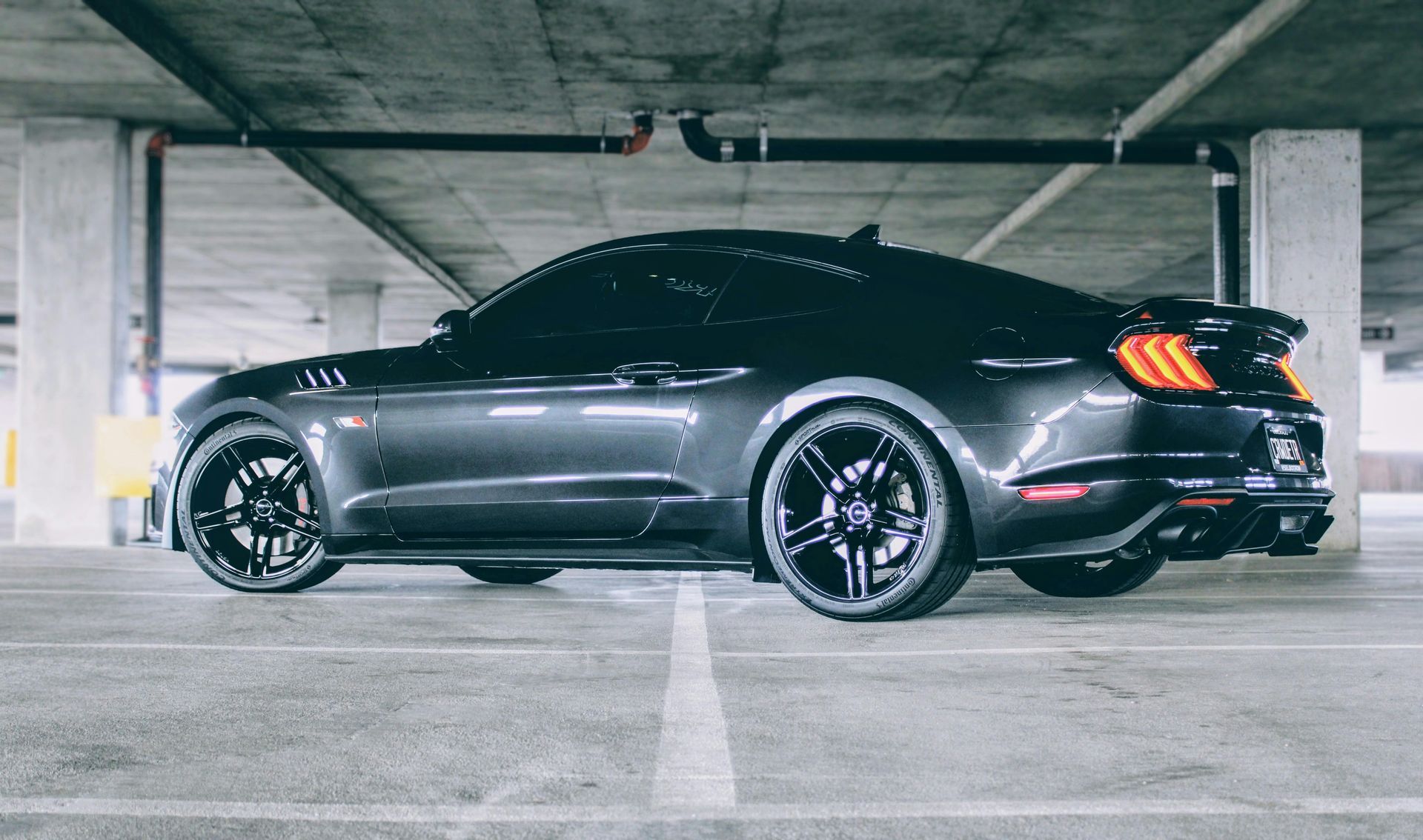 A black mustang is parked in a parking garage.