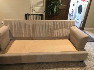 A couch is sitting in a living room next to a washer and dryer.