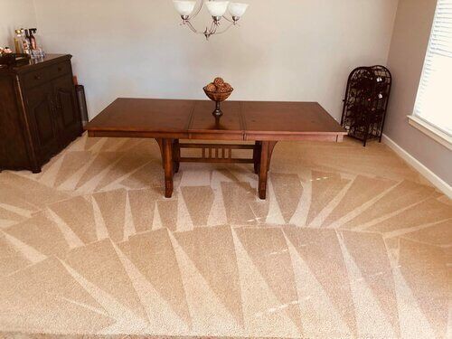 A dining room with a table and chairs and a rug on the floor.