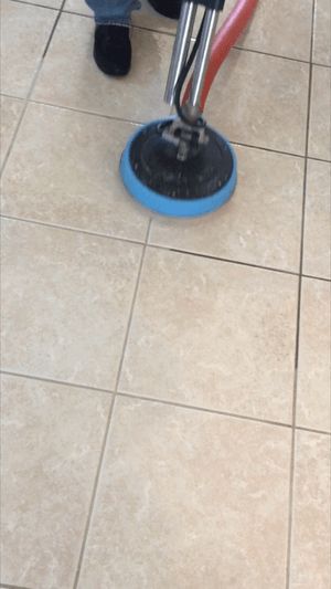 A person is cleaning a tiled floor with a machine.