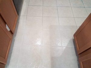 A kitchen with tile floors and wooden cabinets.