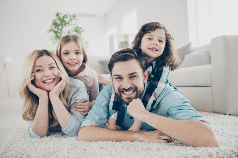 A family is laying on the floor in a living room.