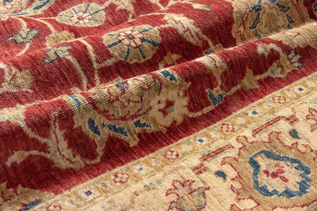 A close up of a red and tan rug with a floral pattern.