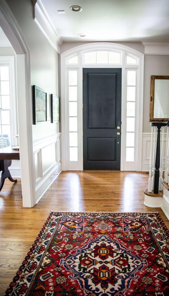 A hallway with a rug and a black door.