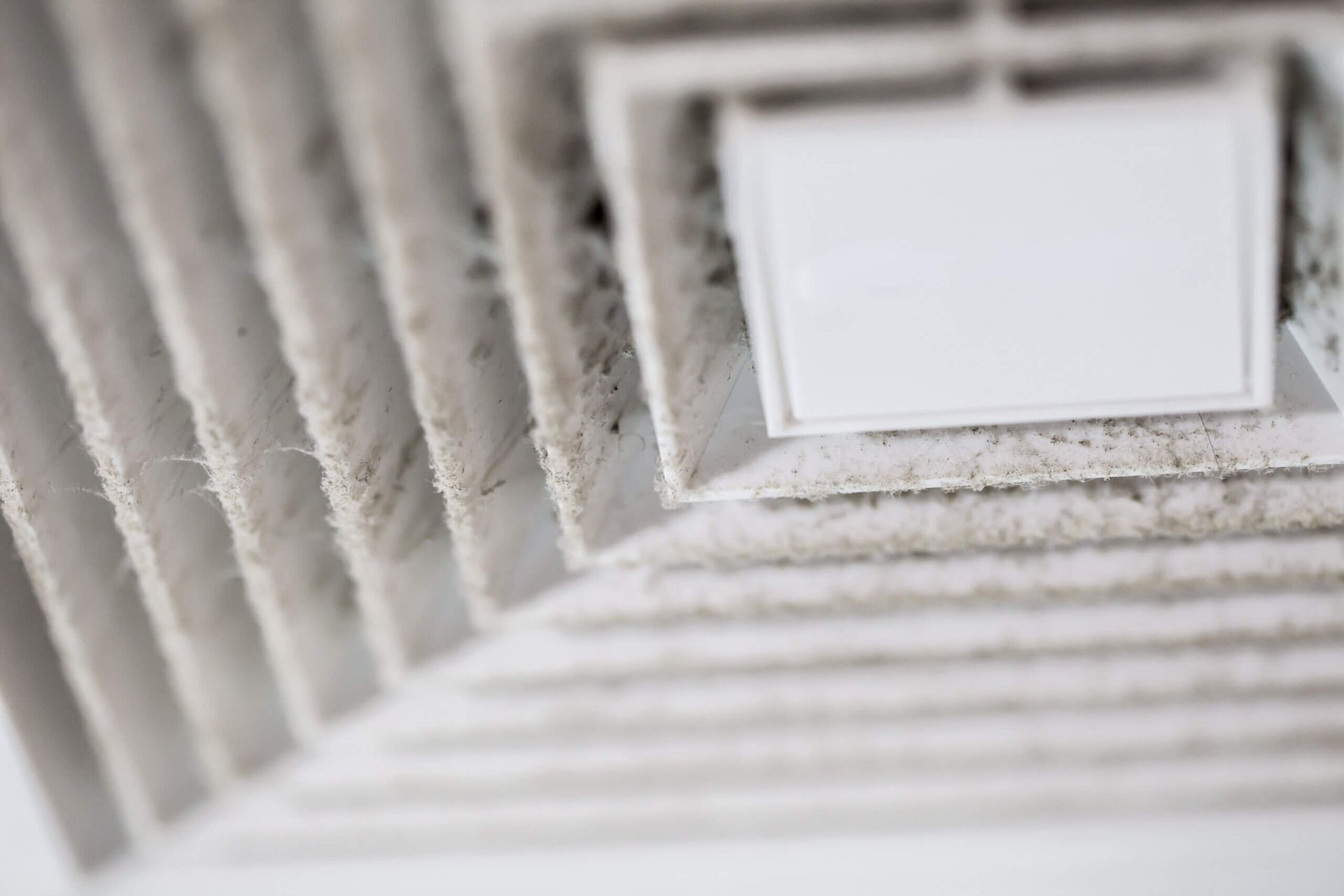 A close up of a dirty air vent in a room.