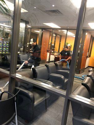 A man is cleaning a waiting room with a vacuum cleaner.