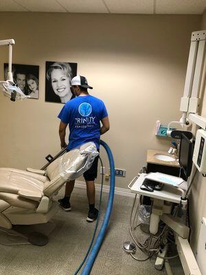 Two men are cleaning a dental office with a vacuum cleaner.