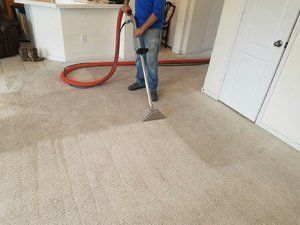 A man is cleaning a carpet with a vacuum cleaner in a living room.