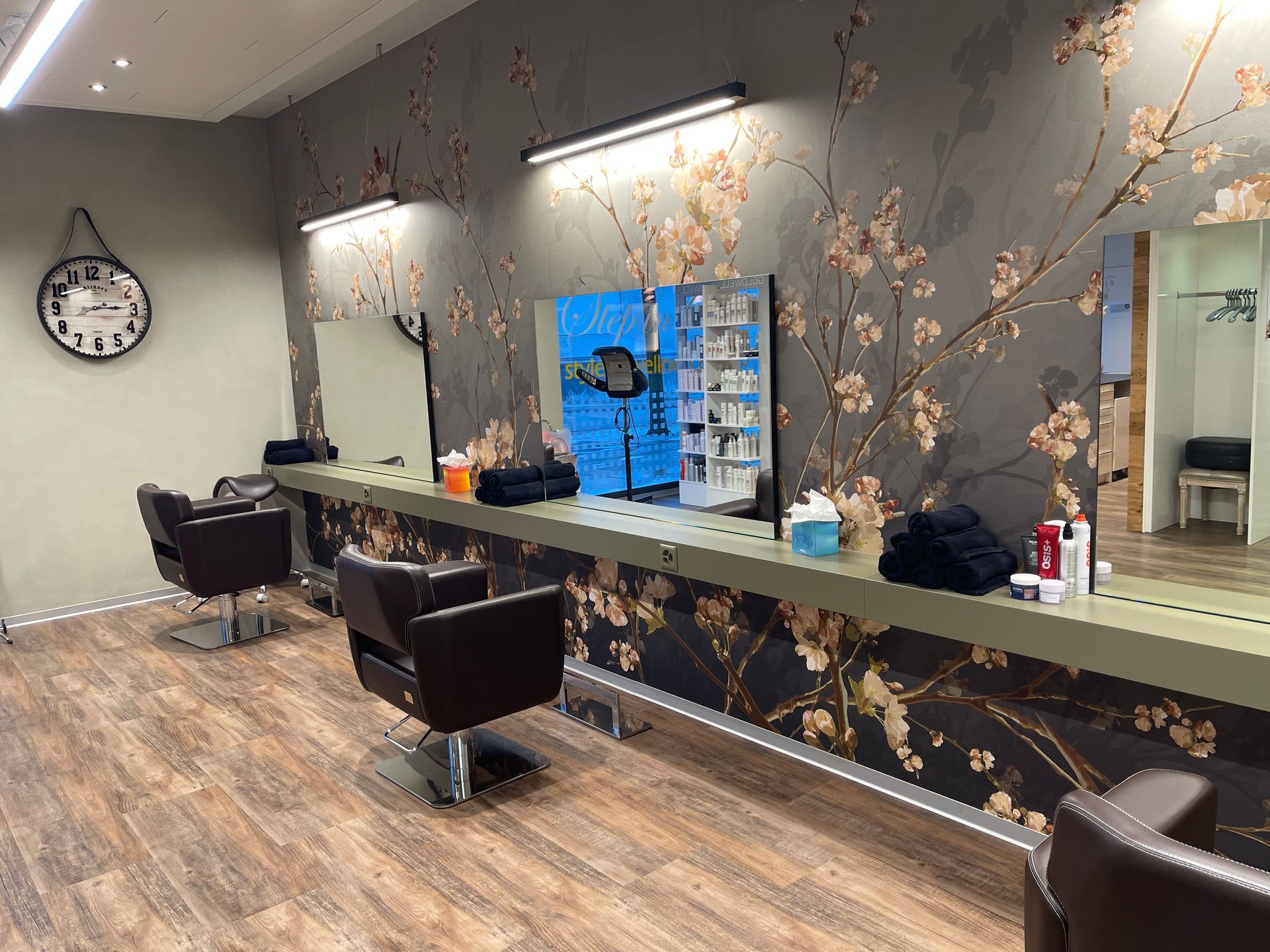 Ein Friseursalon mit Stühlen, Spiegeln und einer Uhr an der Wand.