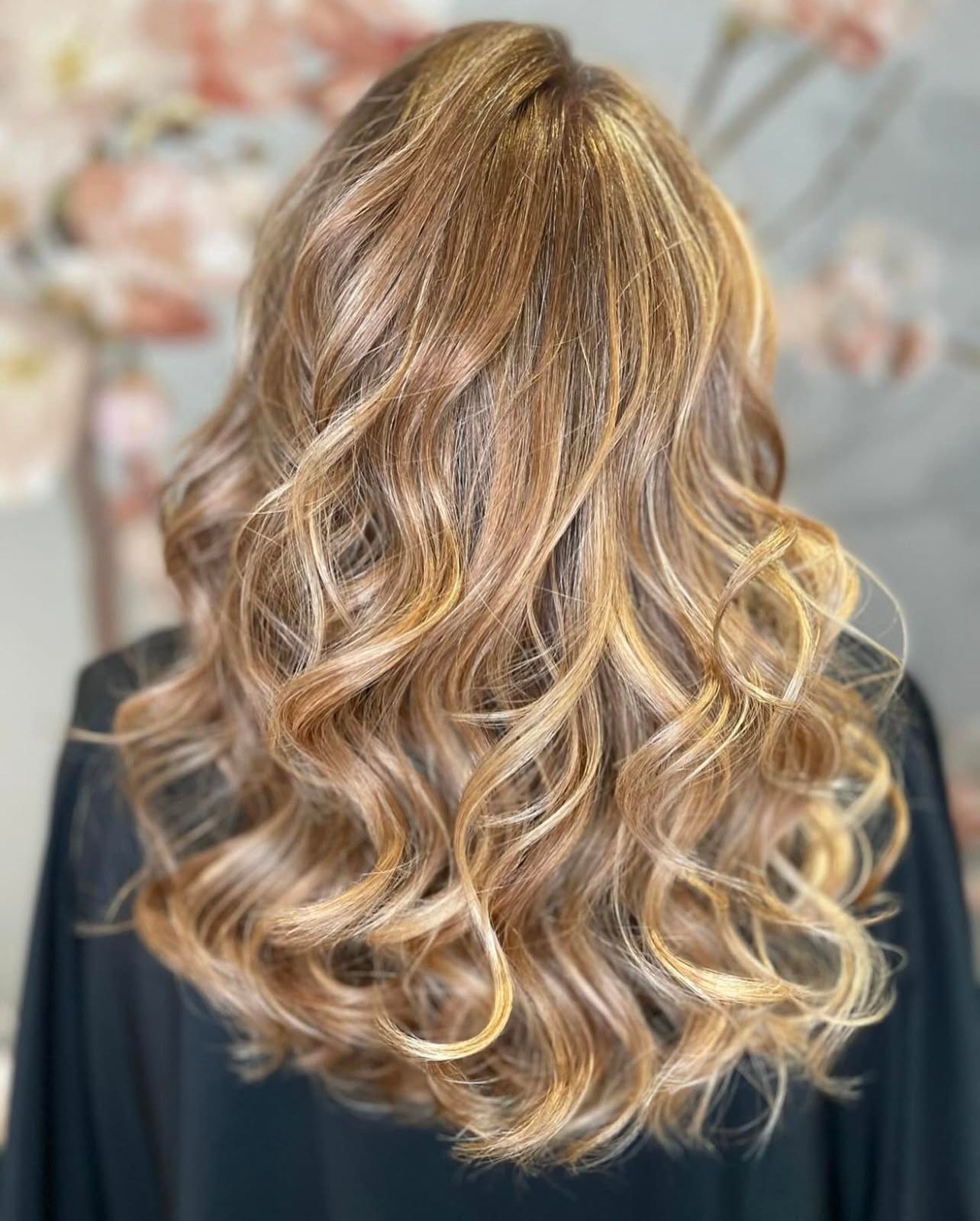 Eine Frau mit langem, welligem, blondem Haar trägt ein schwarzes Hemd.