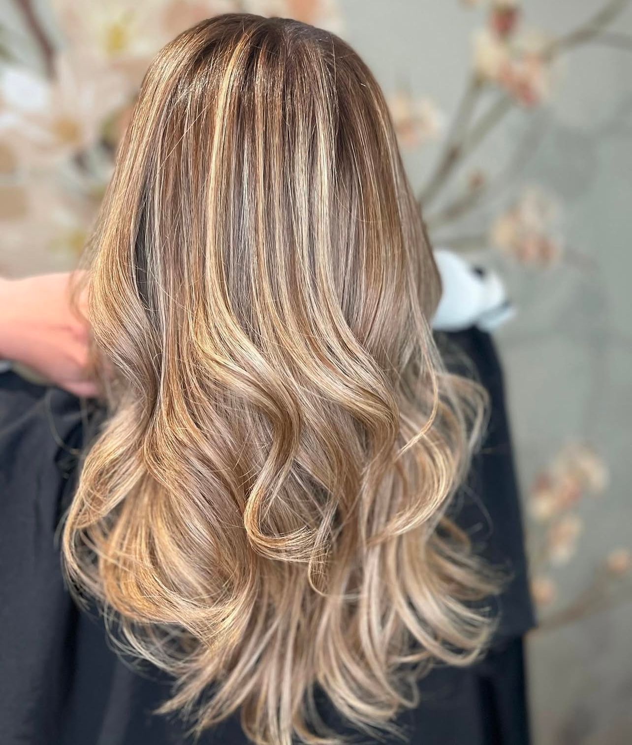 Eine Frau mit langen blonden Haaren lässt sich von einem Friseur die Haare schneiden.