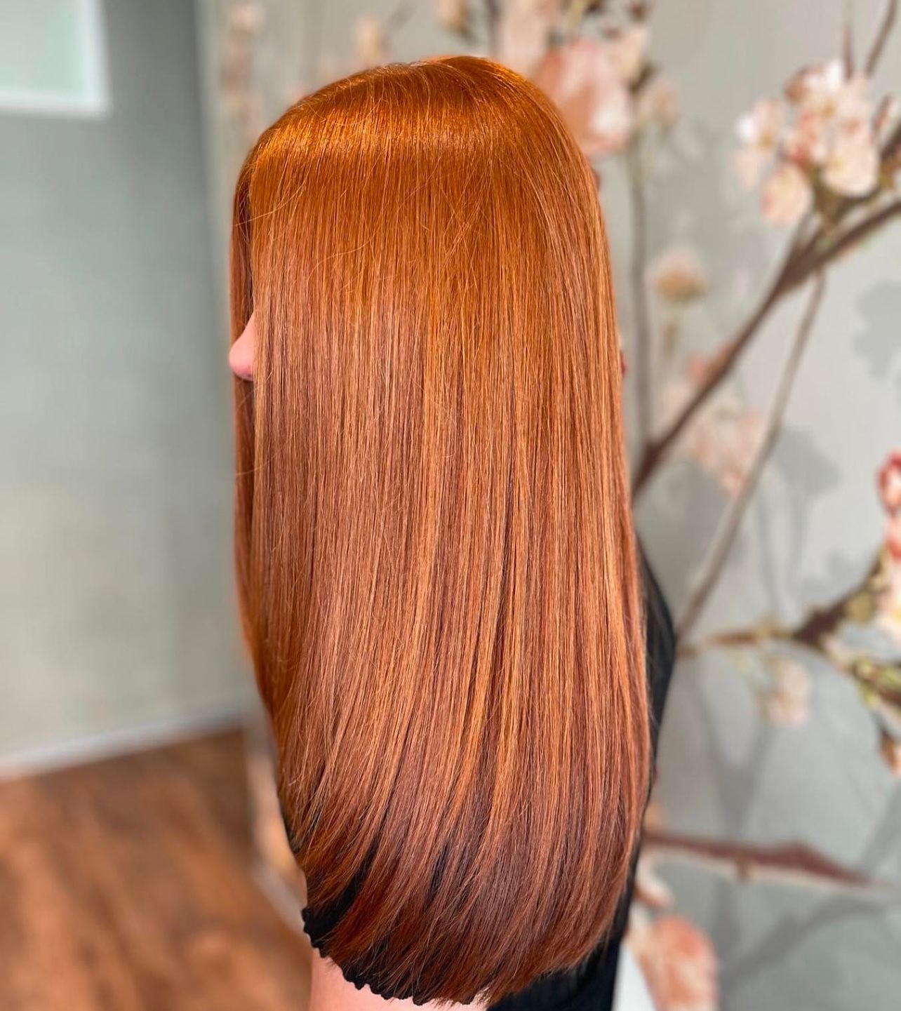 Eine Frau mit langen roten Haaren steht vor einem Kirschblütenbaum.