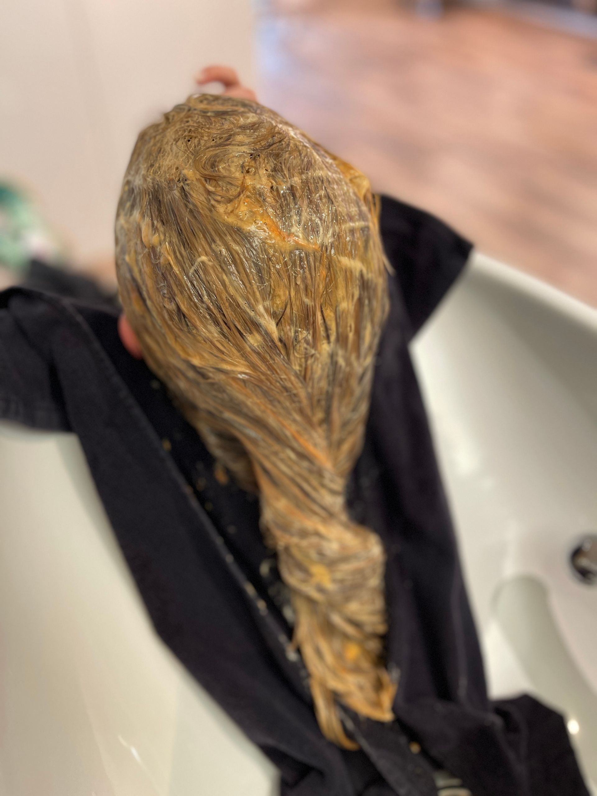 Eine Frau lässt sich in einem Waschbecken die Haare färben.