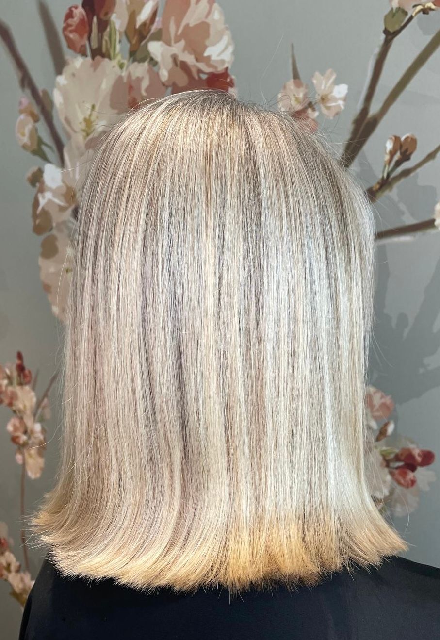 Eine Frau mit blonden Haaren sitzt vor einem Baum mit Blumen.