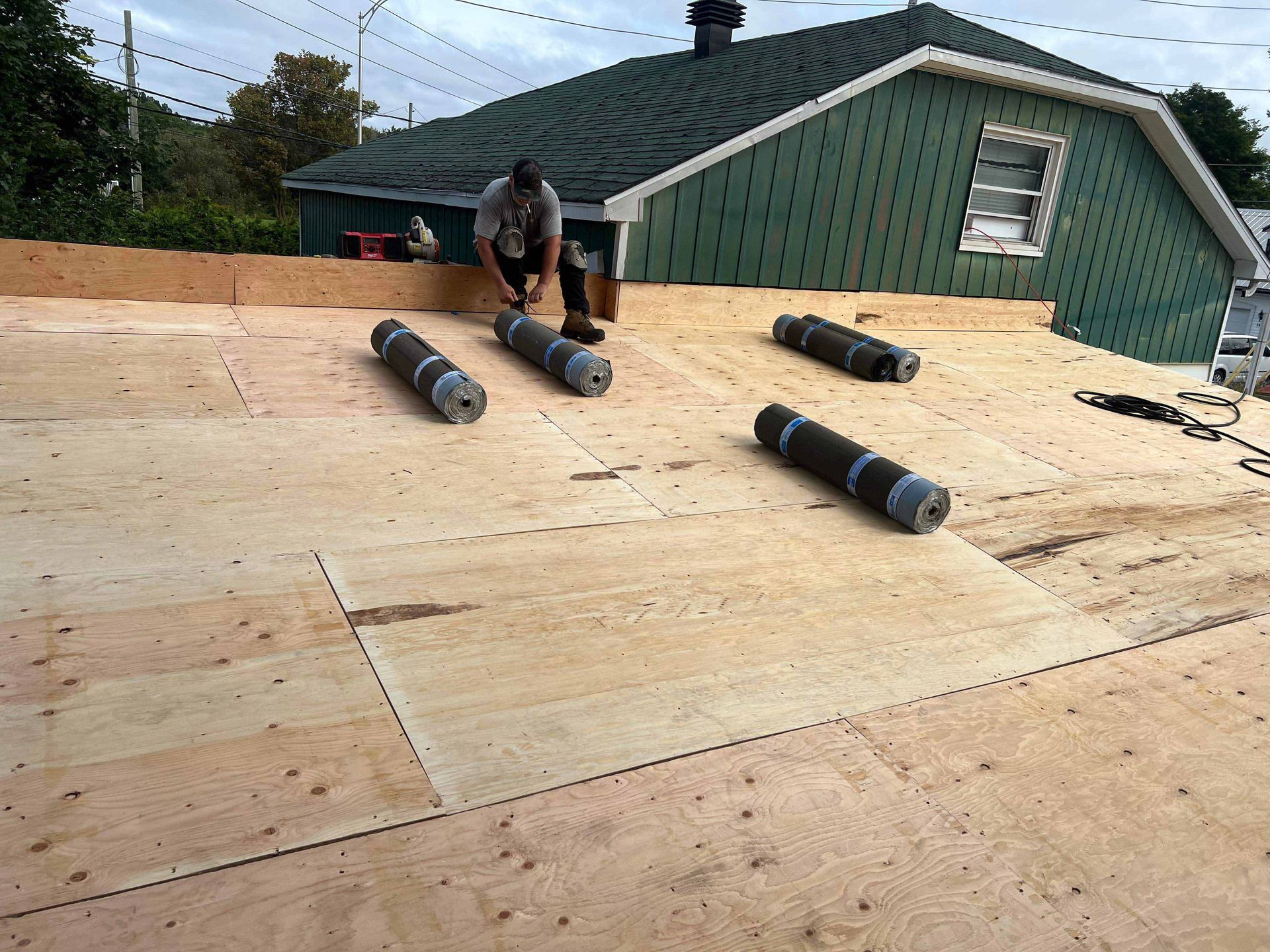Gros plan sur des bardeaux de toiture en asphalte usés par les intempéries, dans des tons de gris et de brun, certains se recourbant.