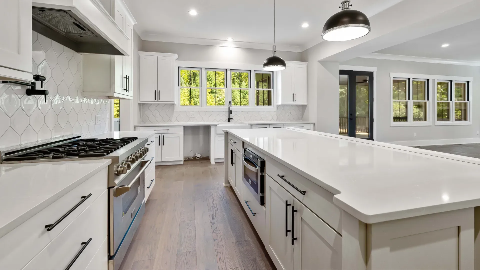 A kitchen with white cabinets , stainless steel appliances , and a large island.