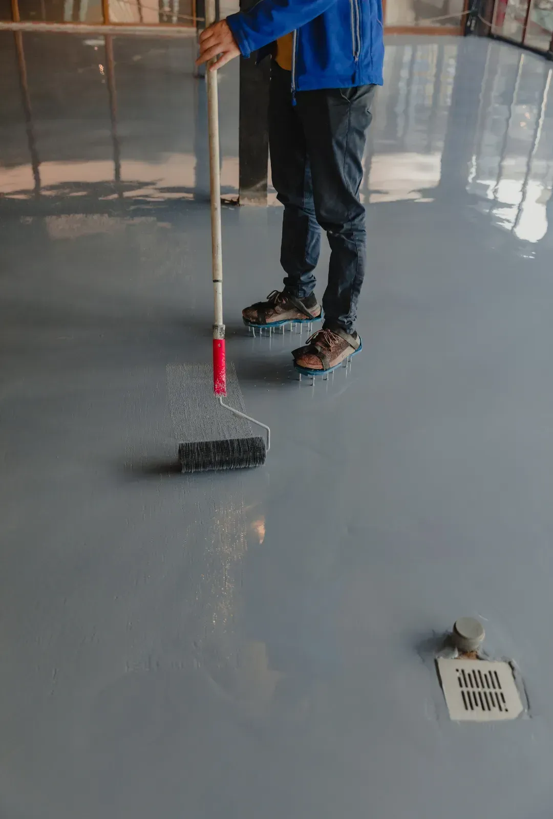 A man is painting a concrete floor with a roller.