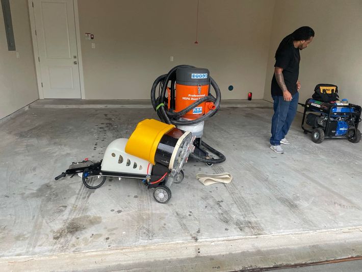 A man is standing next to a vacuum cleaner in a garage.