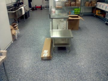 A kitchen with a stainless steel table and boxes on the floor