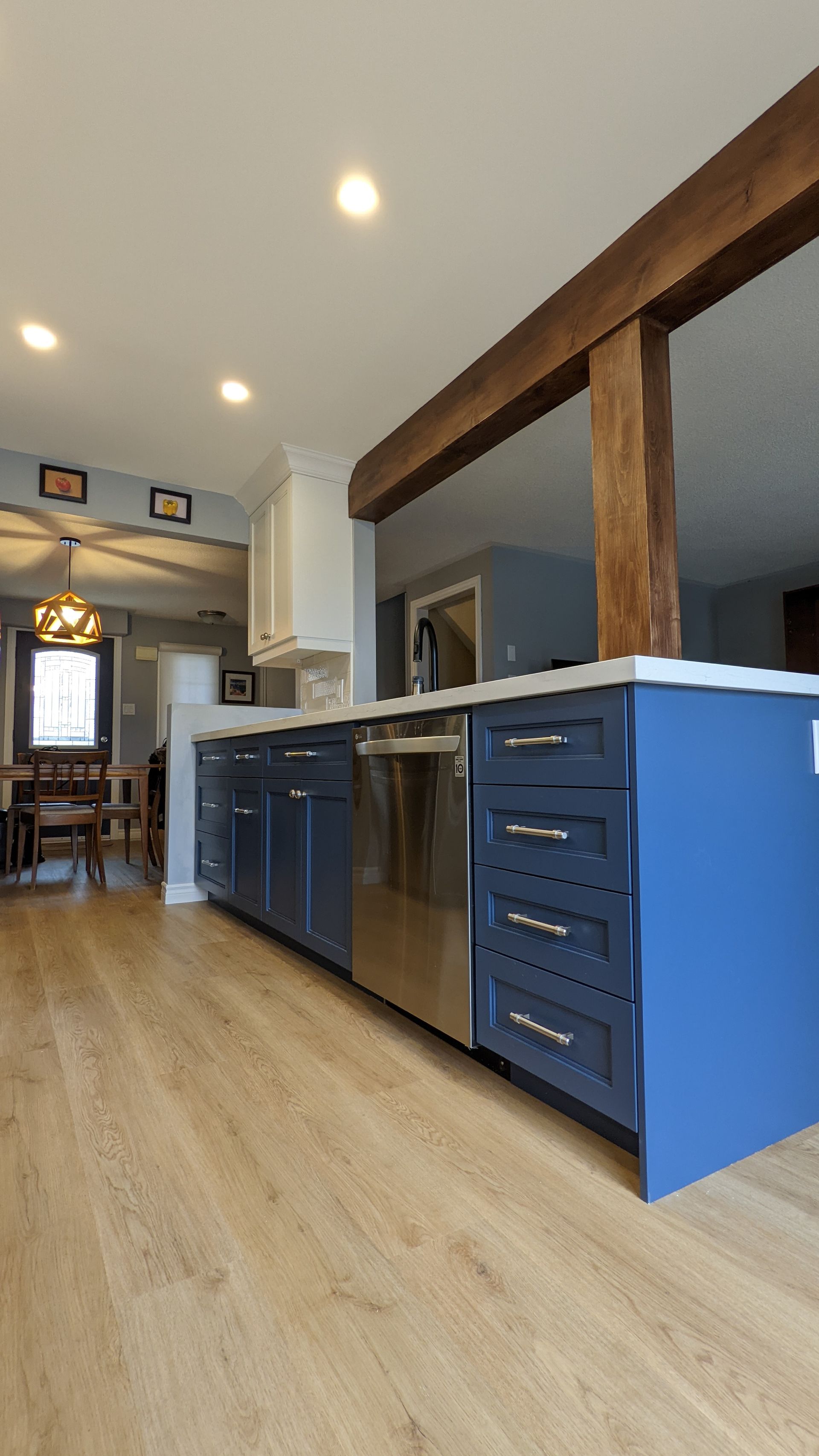 A kitchen with blue cabinets , stainless steel appliances , and a wooden floor.