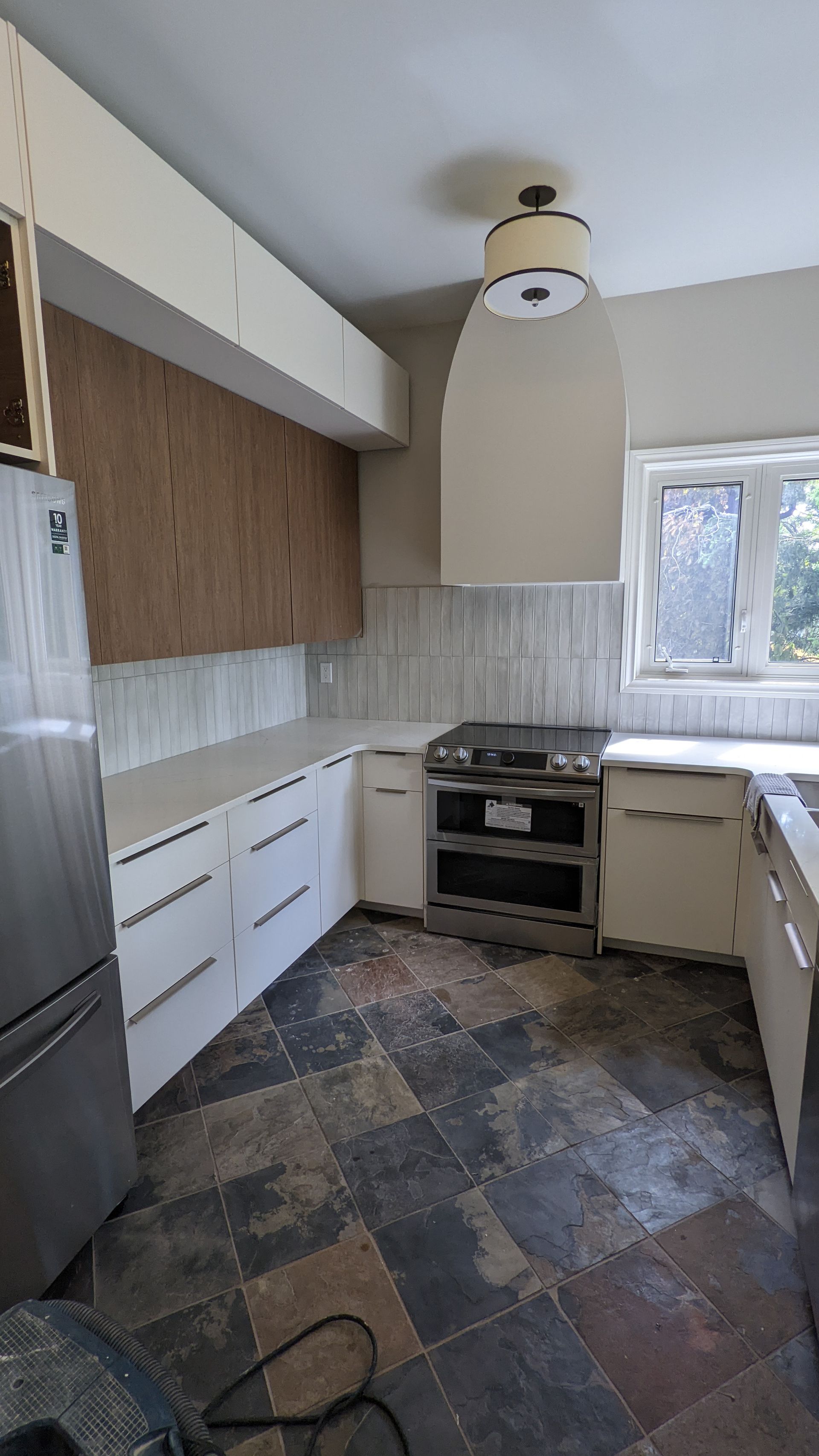 A kitchen with stainless steel appliances , a refrigerator , a stove , and a window.