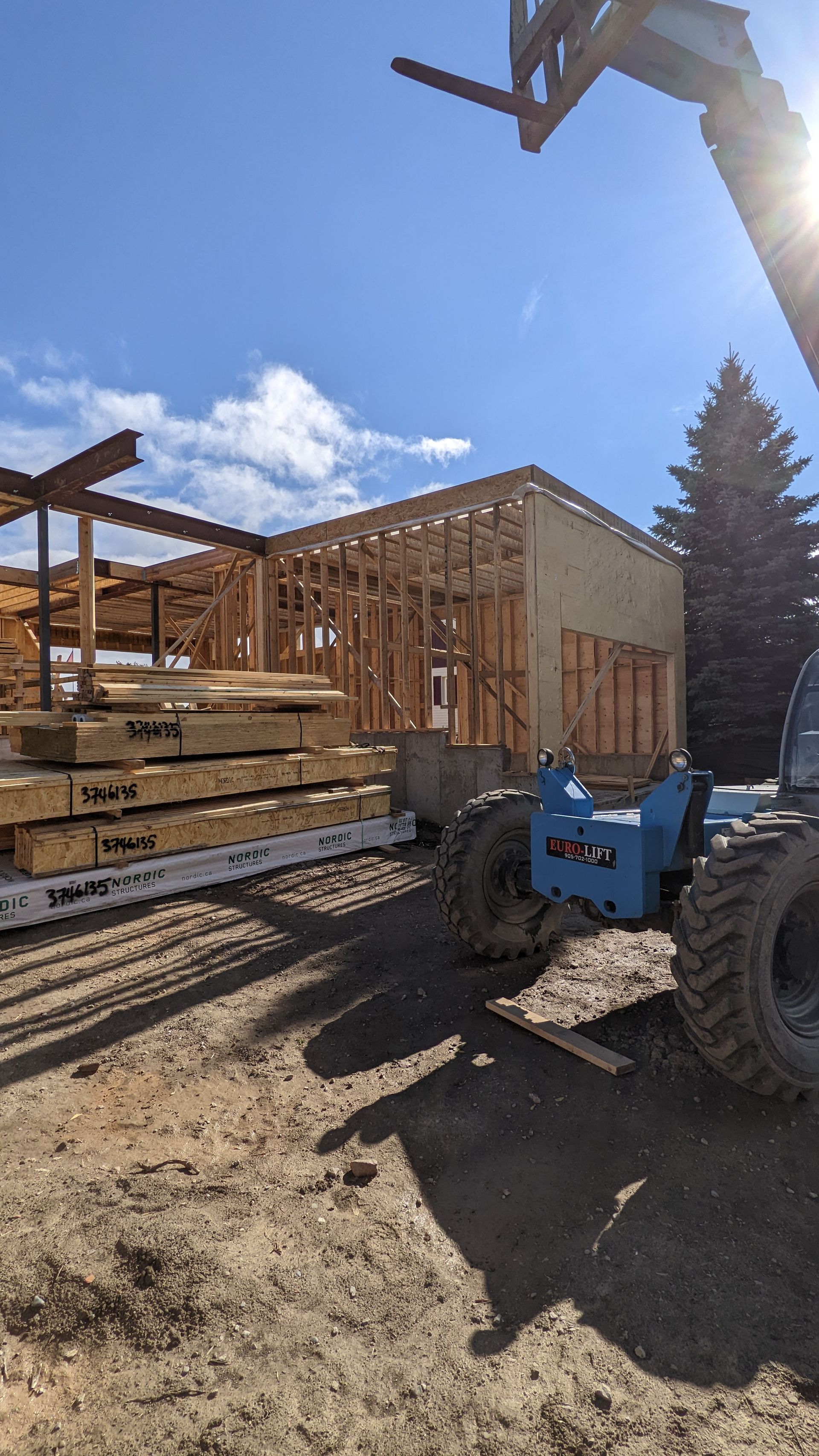 A forklift is carrying a stack of wood on a trailer.