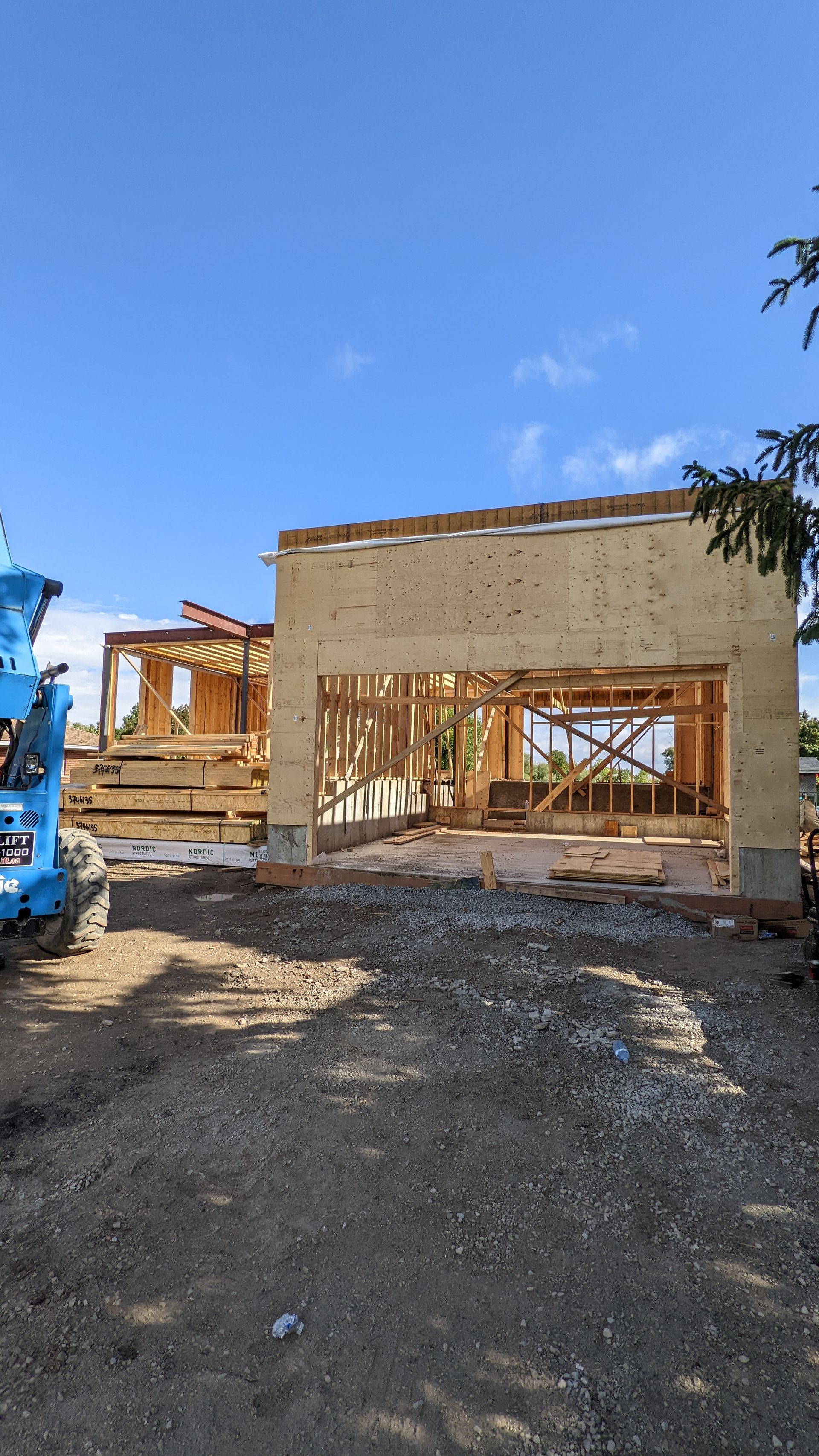 A blue truck is parked in front of a house under construction.