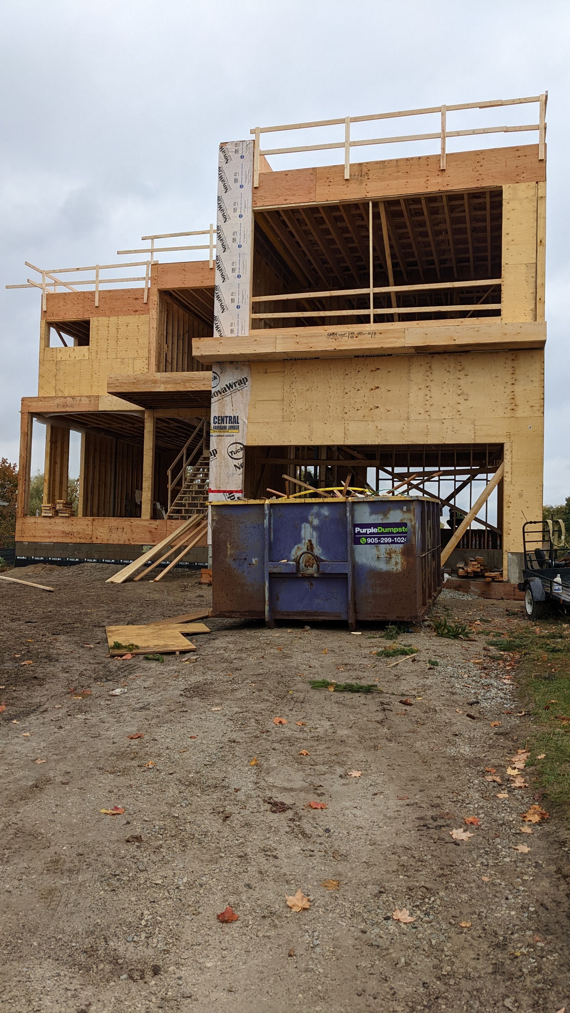 A large wooden house is being built on a dirt road.