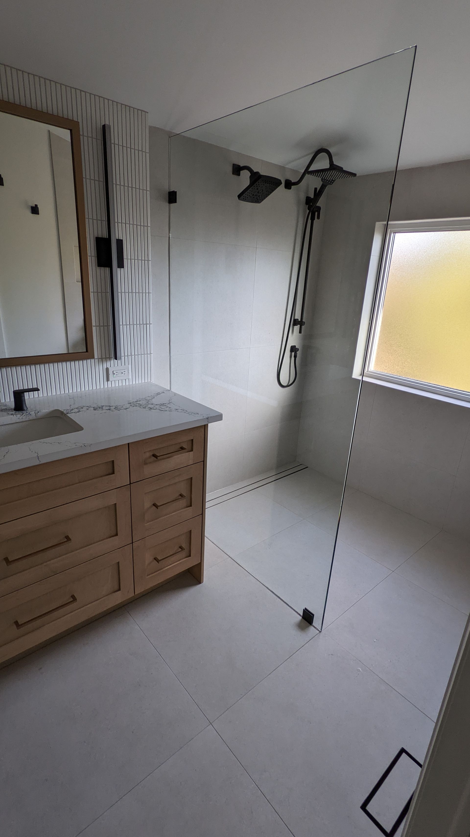 A bathroom with a sink , mirror and walk in shower.