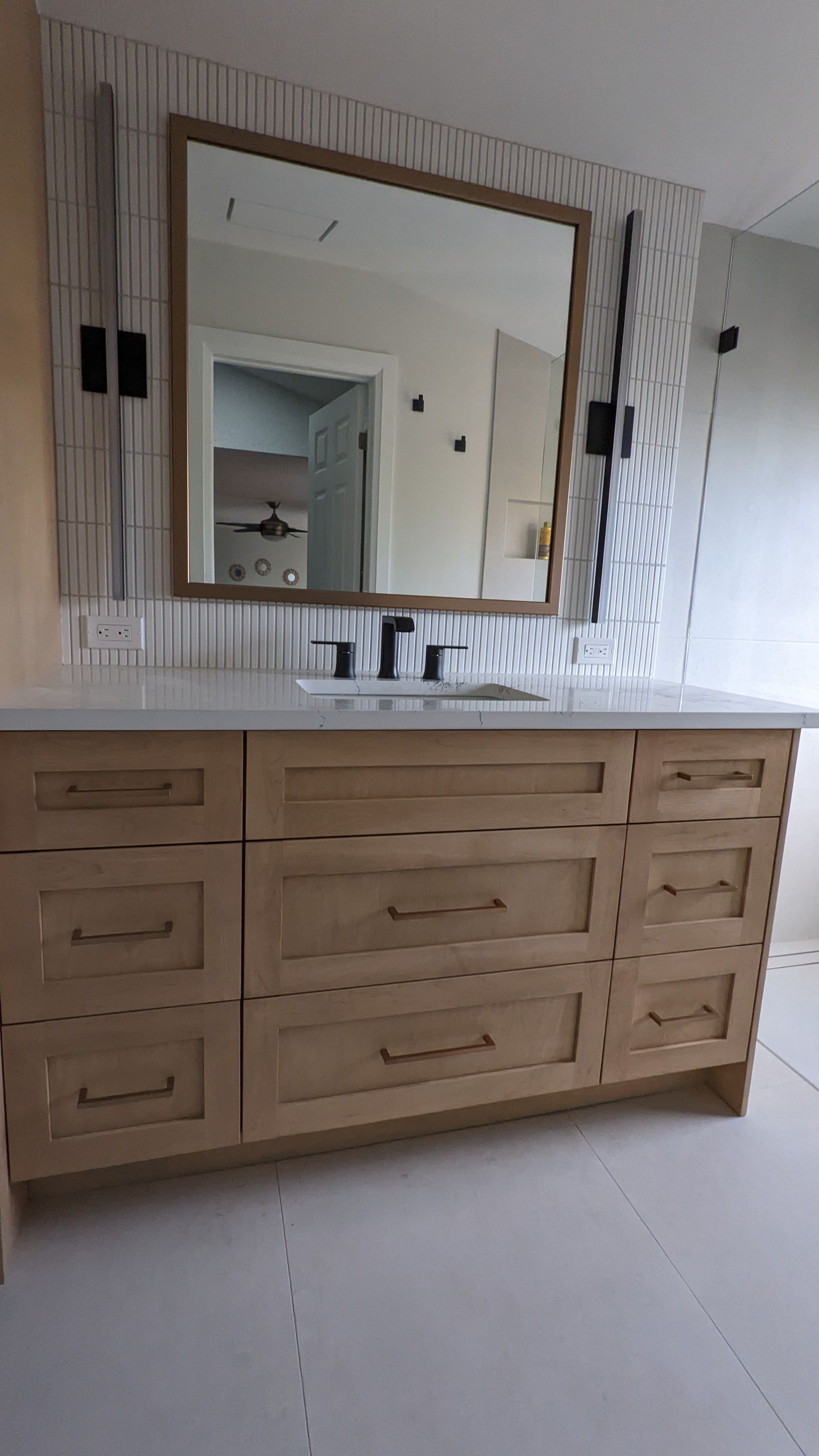 A bathroom with a sink , mirror and wooden cabinets.