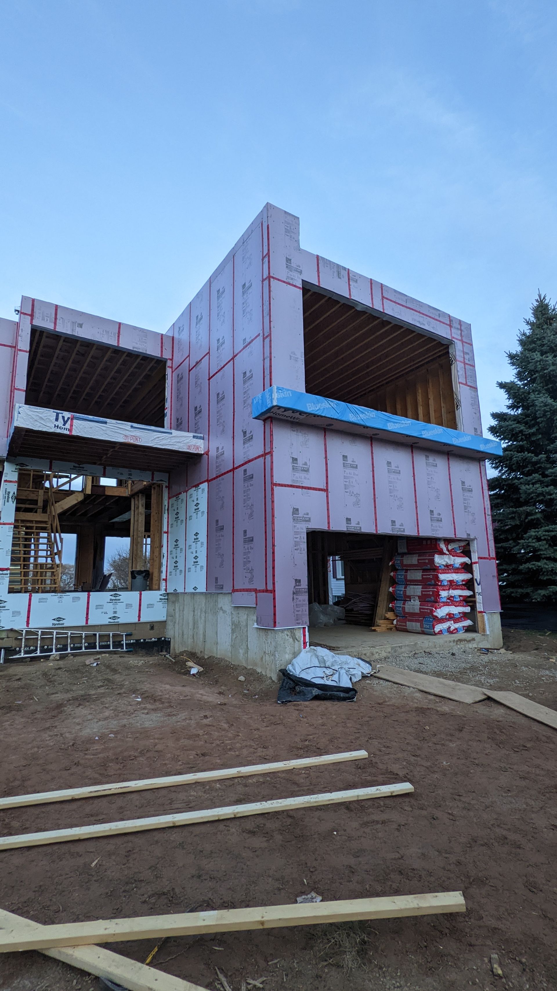 A large house is being built in the middle of a dirt field.