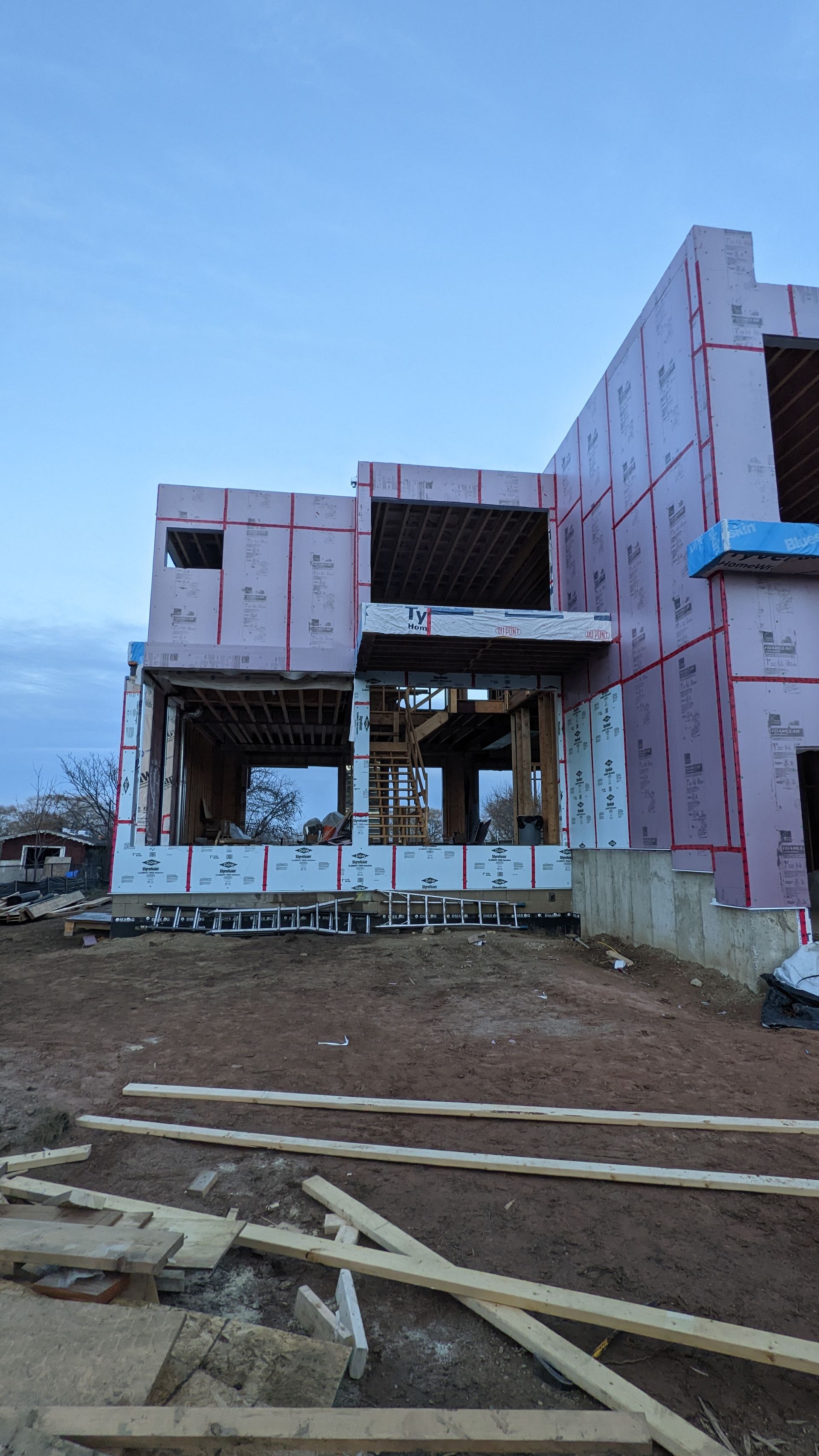 A large house is being built in the middle of a dirt field.