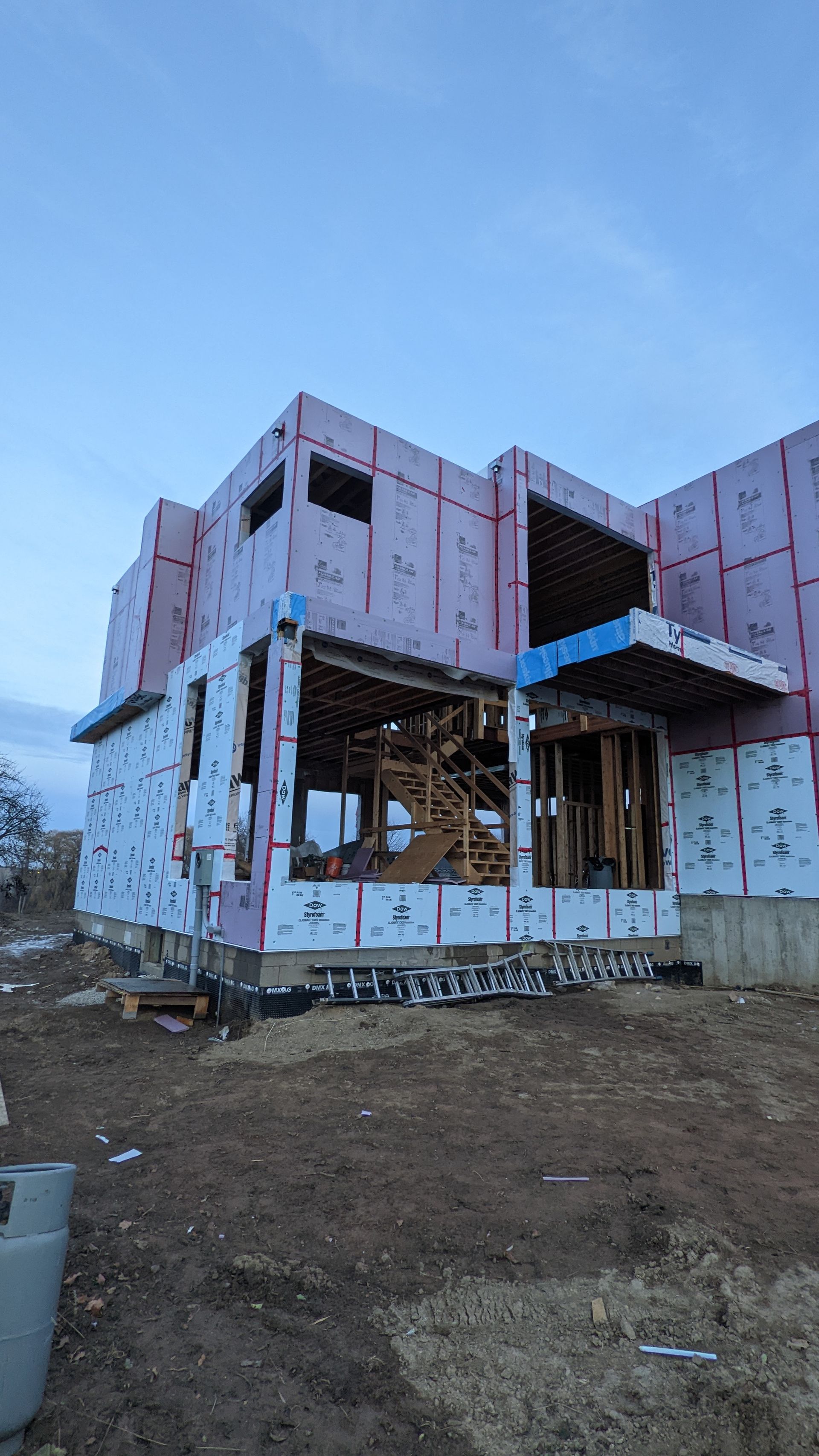 A large house is being built in the middle of a dirt field.