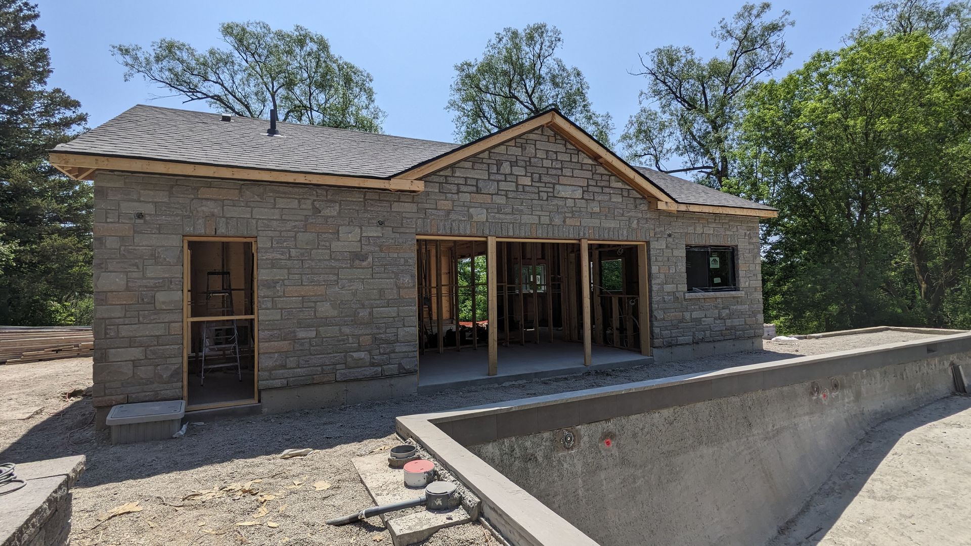 A stone house is being built next to a swimming pool.
