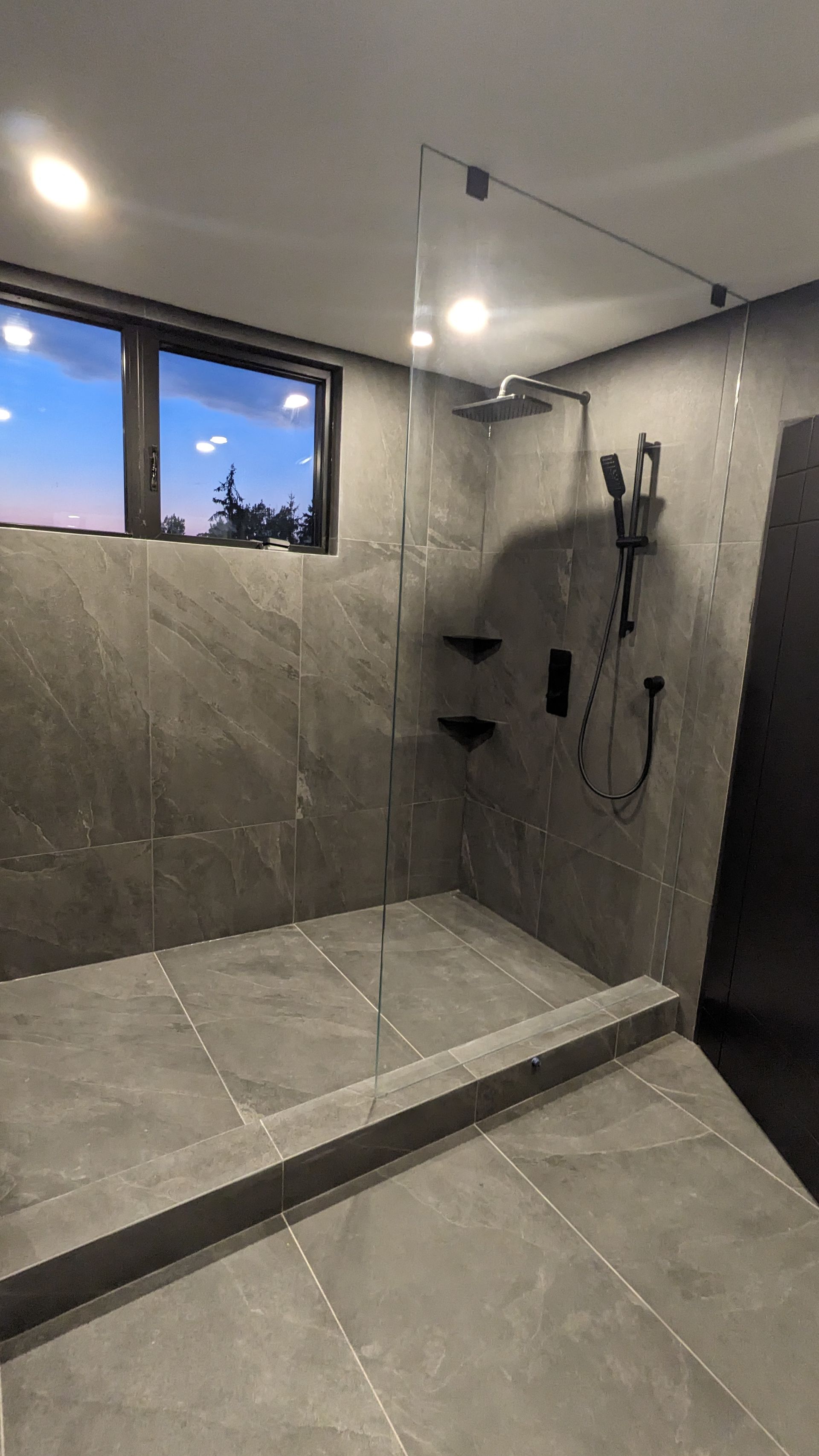A bathroom with a walk in shower and a window.