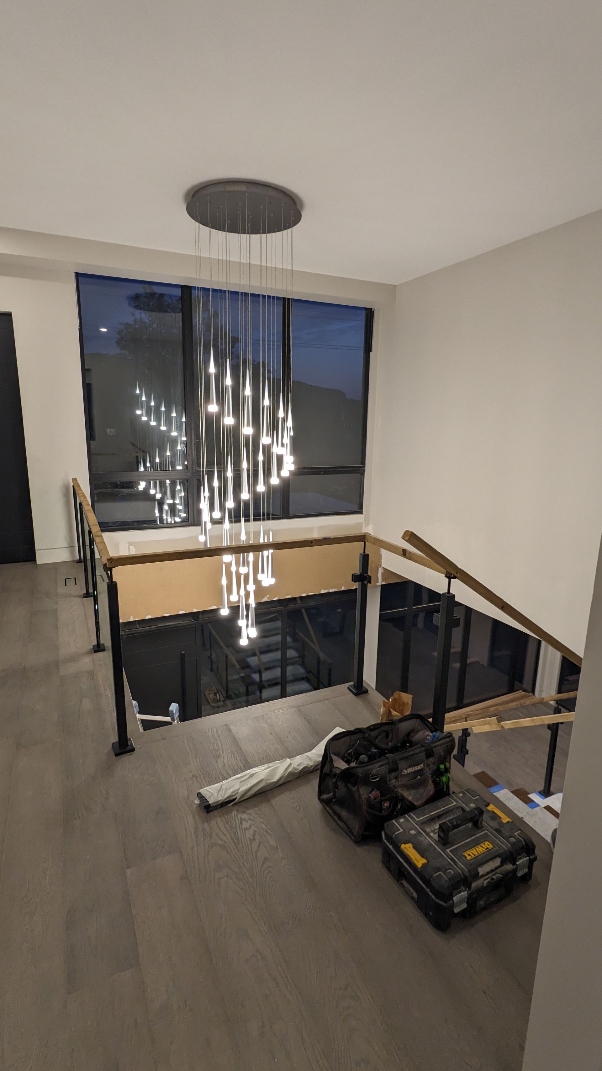 A large chandelier is hanging from the ceiling in a room with stairs.
