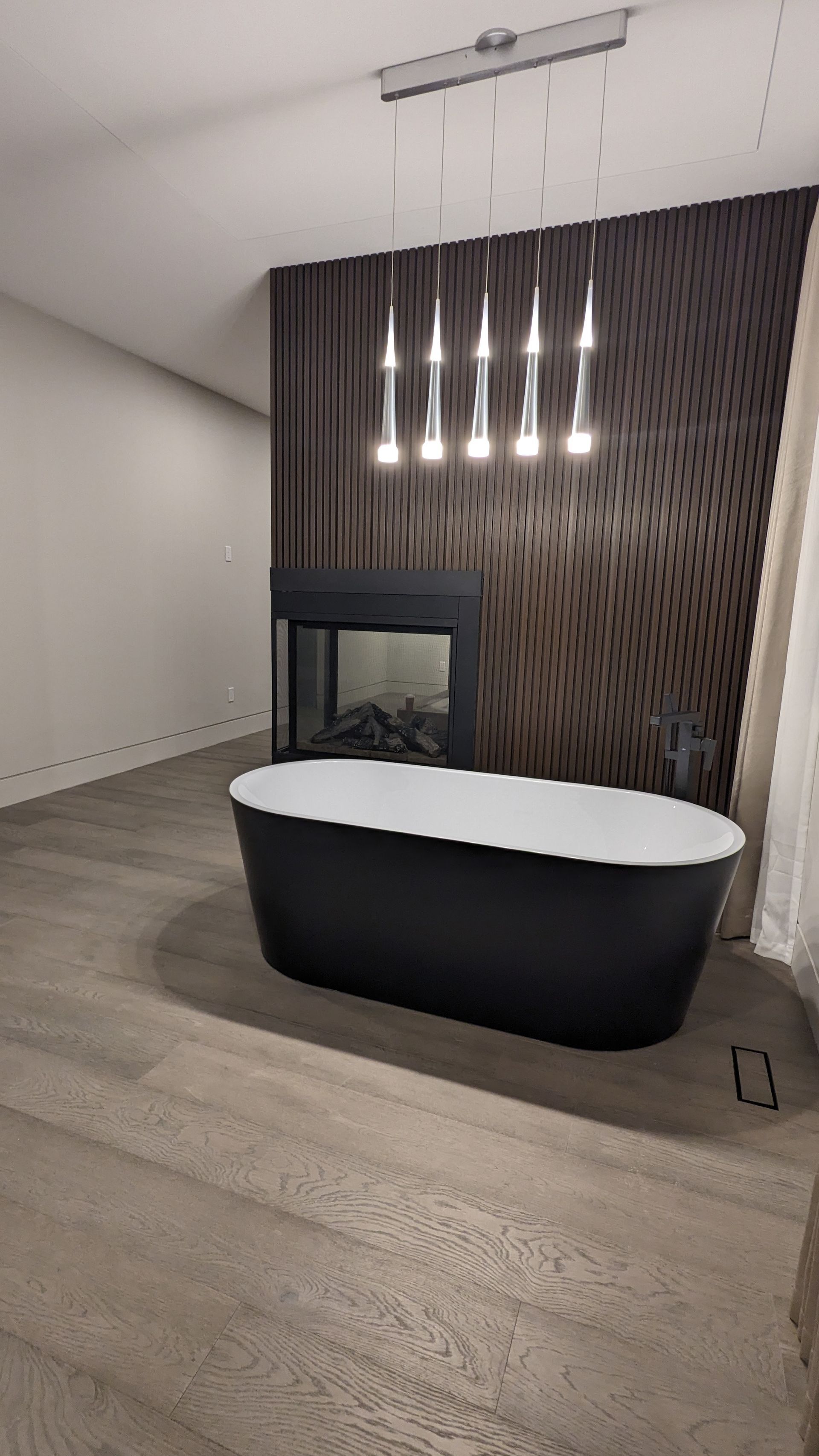 A black bathtub is sitting in a room next to a fireplace.