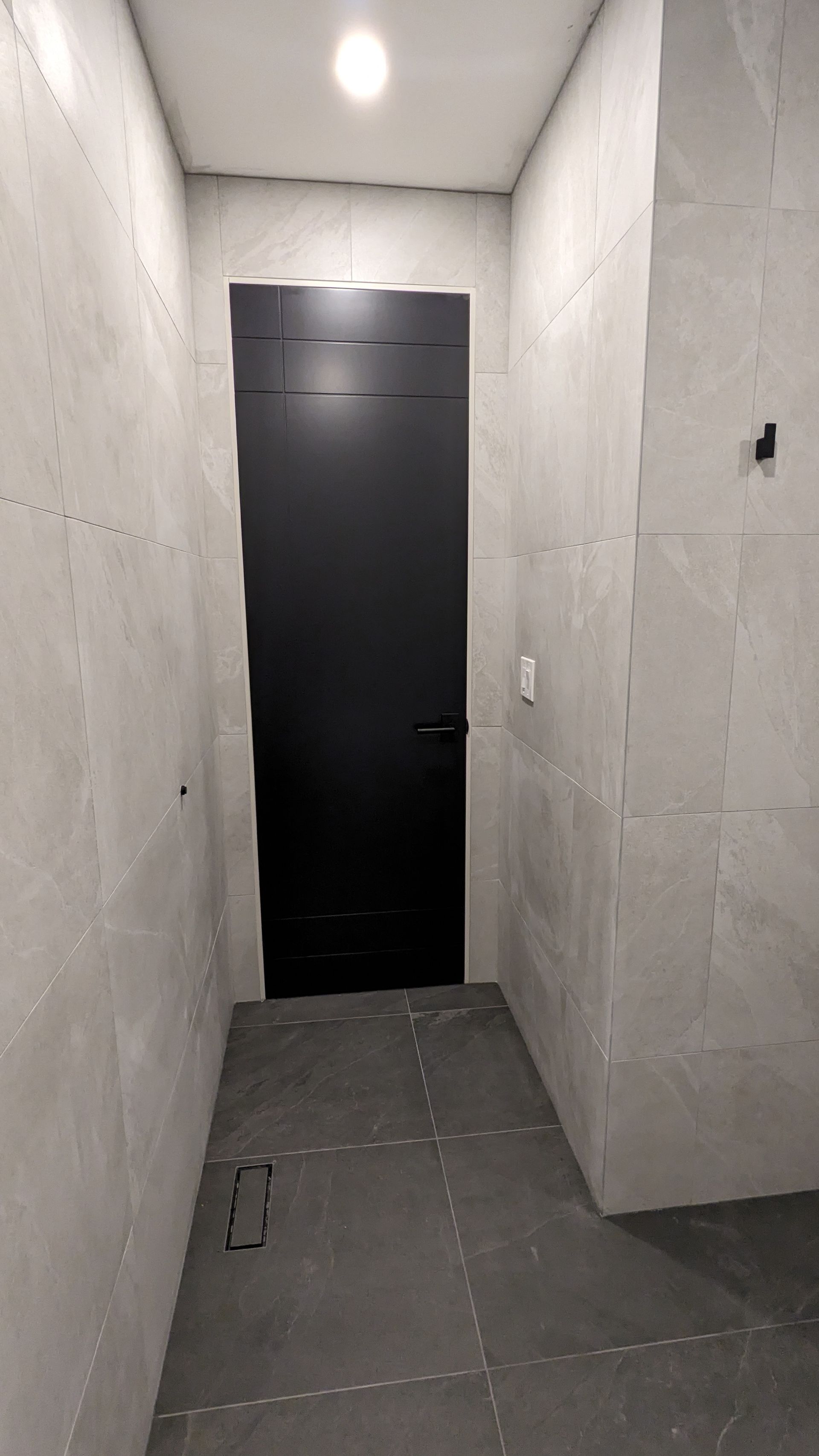 There is a black door in the middle of a hallway.