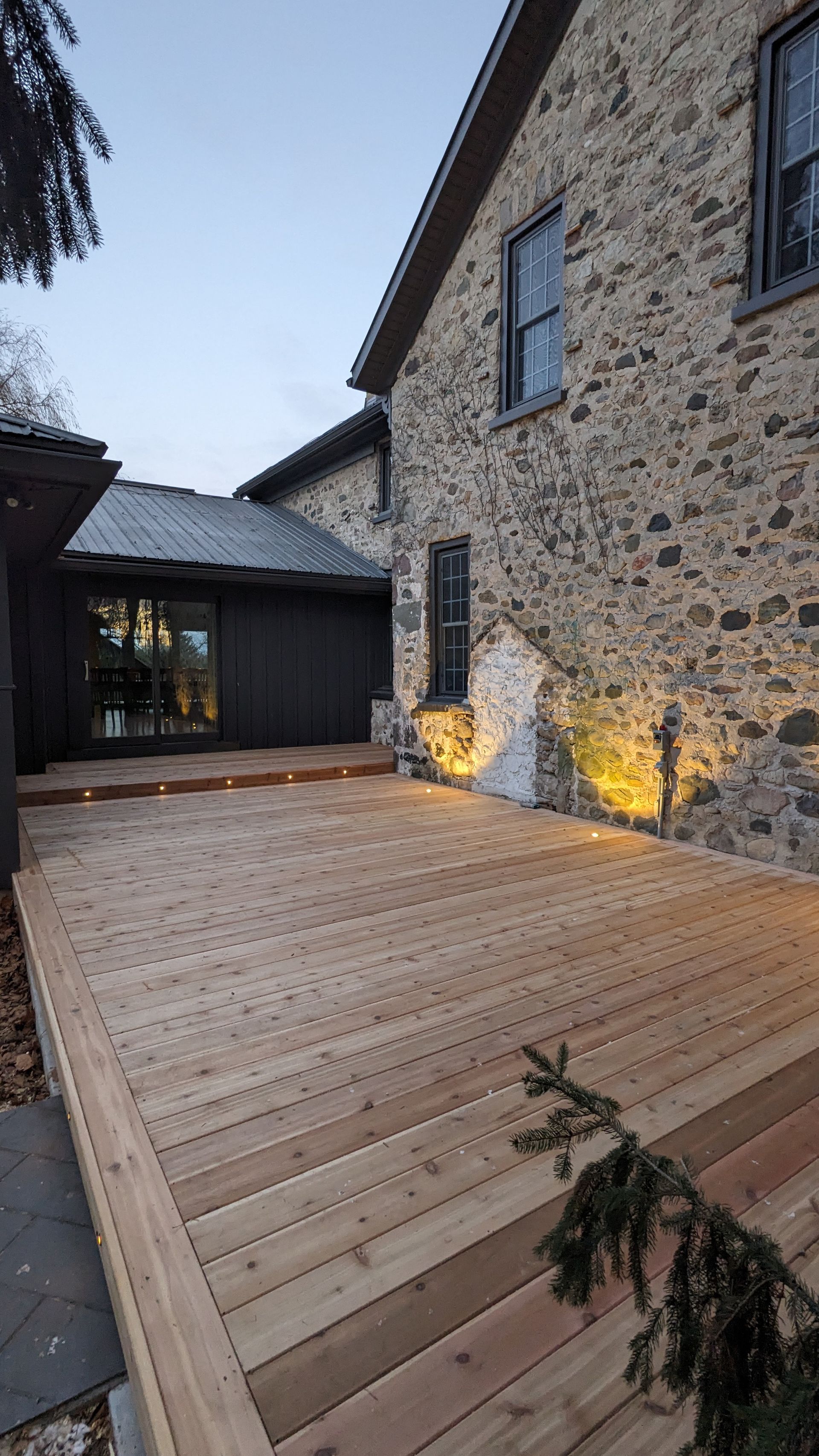 There is a wooden deck in front of a stone building.