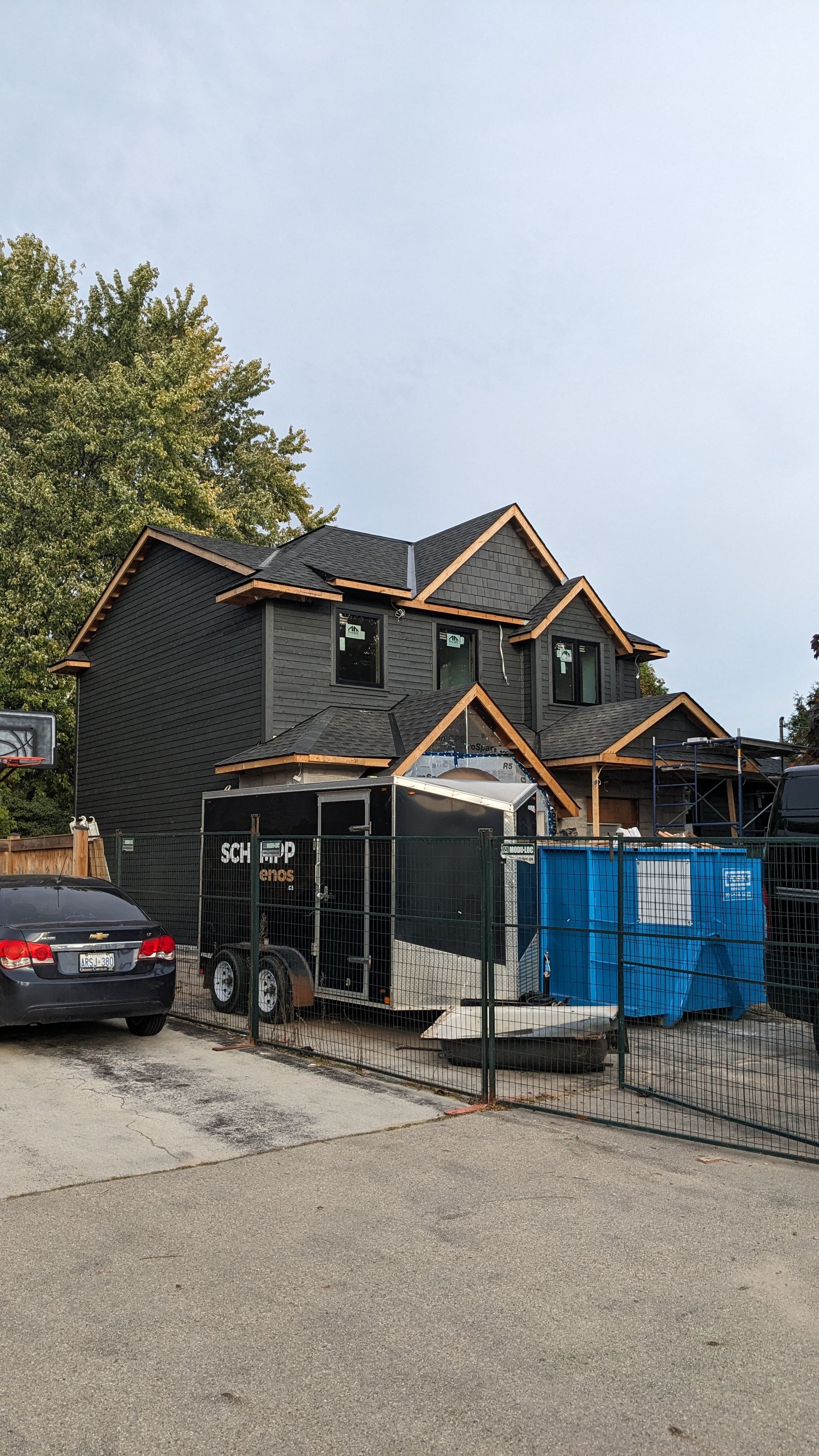A car is parked in front of a house under construction.
